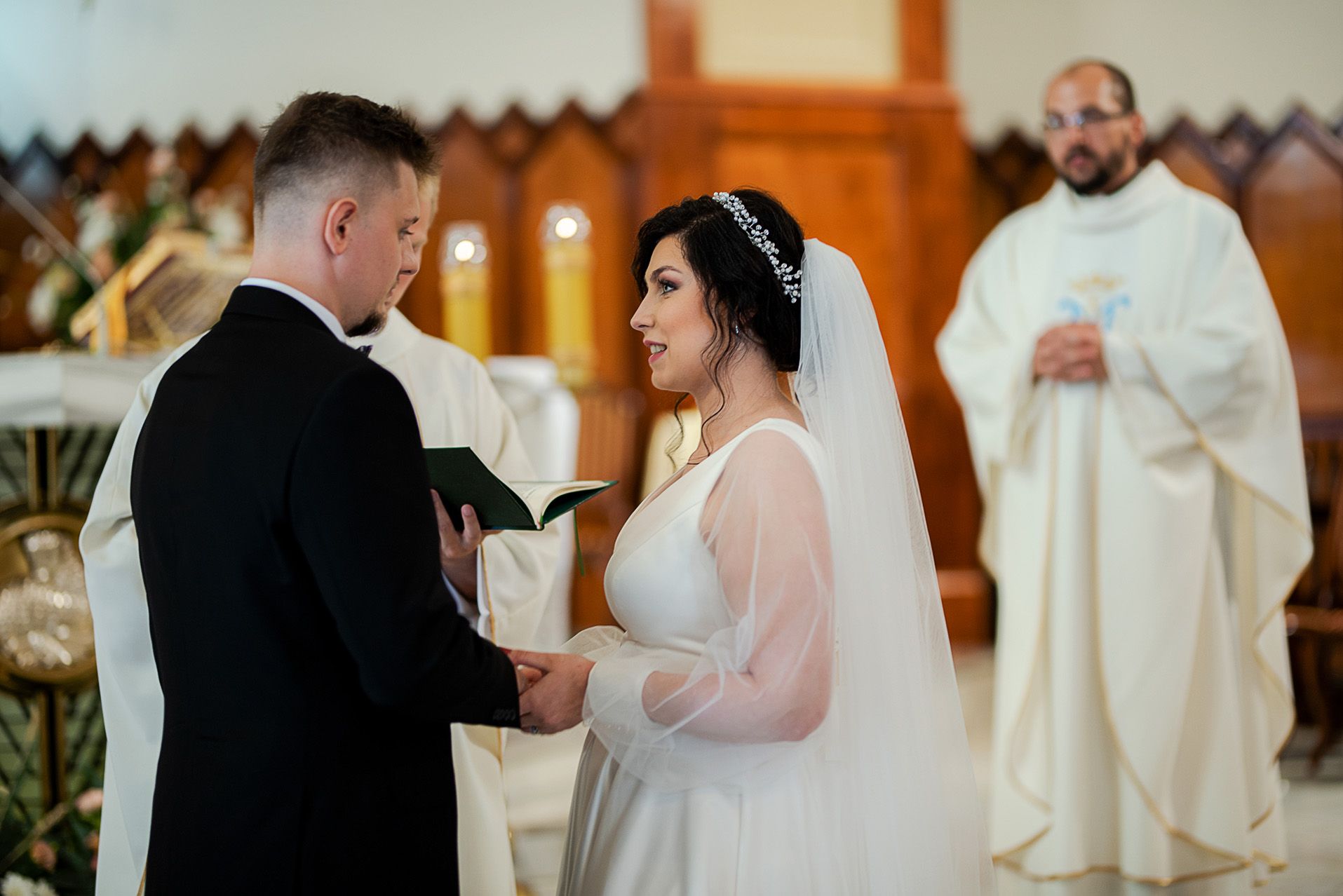 Ceremonia ślubna w kościele z księdzem celebrującym mszę świętą przy ołtarzu, para młoda podczas wymiany ślubowań małżeńskich