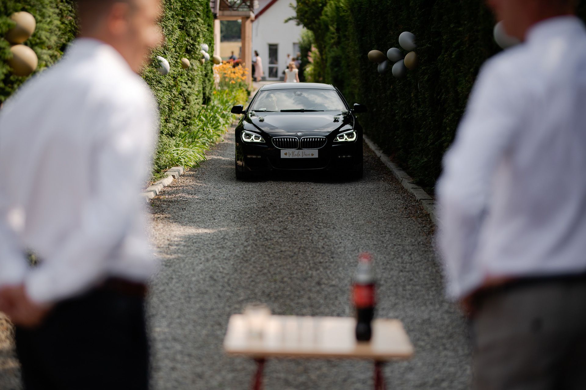 Czarne BMW jako samochód ślubny zaparkowany na podjeździe przed domem z dekoracjami