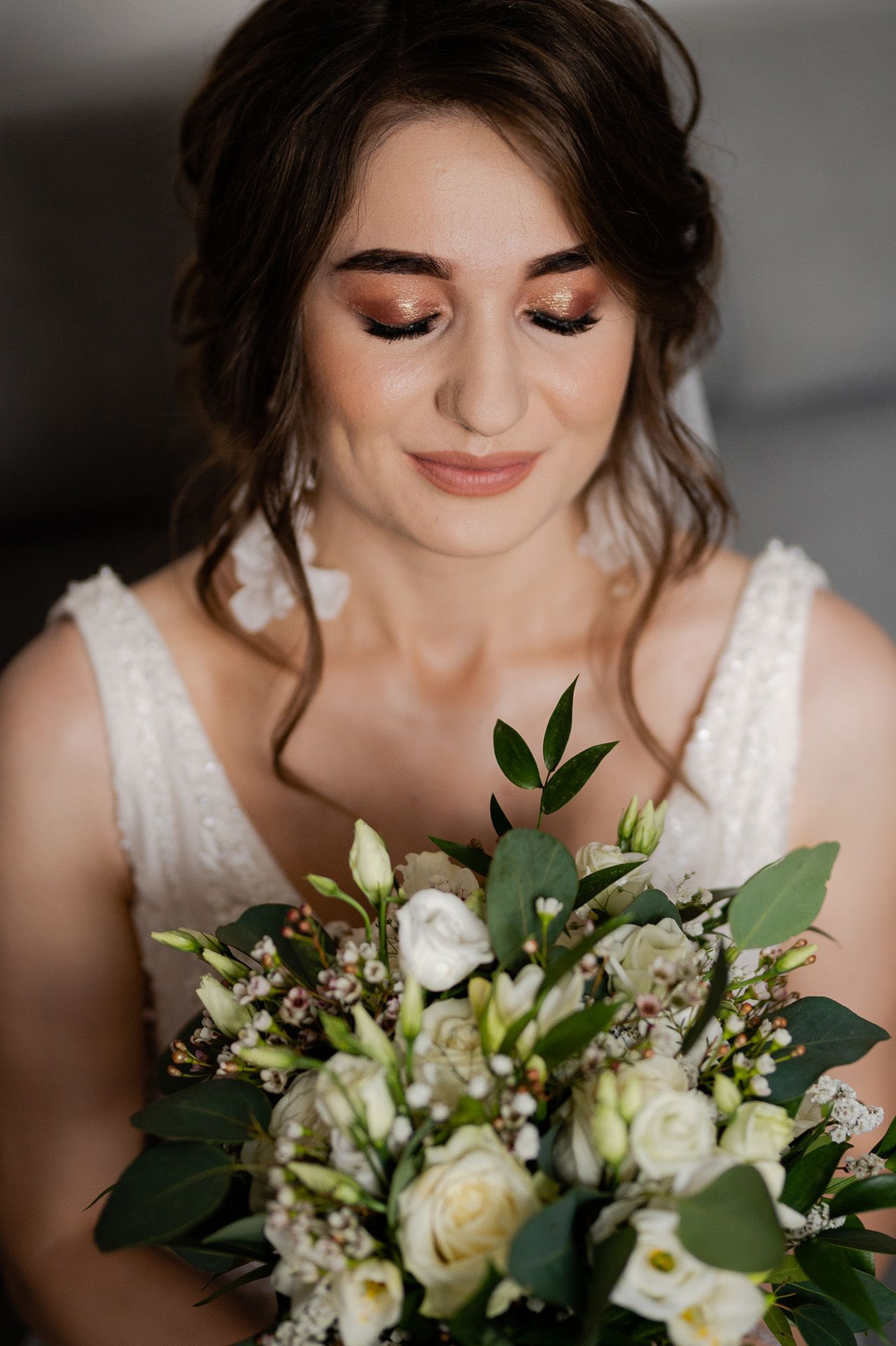 Panna młoda z bukietem białych róż, złotym makijażem oczu i rozpuszczonymi włosami