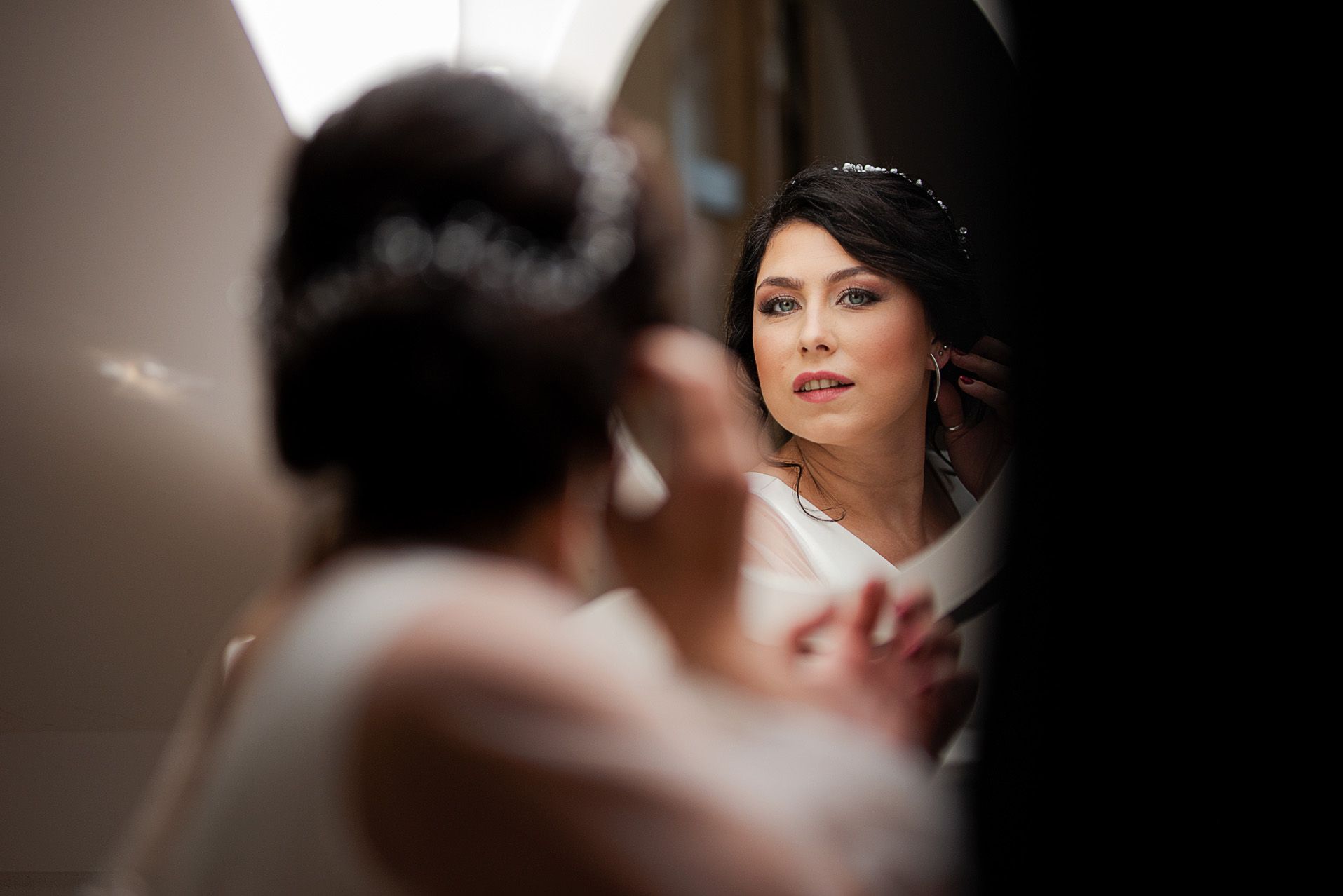 Odbicie panny młodej w koronkowej sukni patrzące w lustro podczas przygotowań