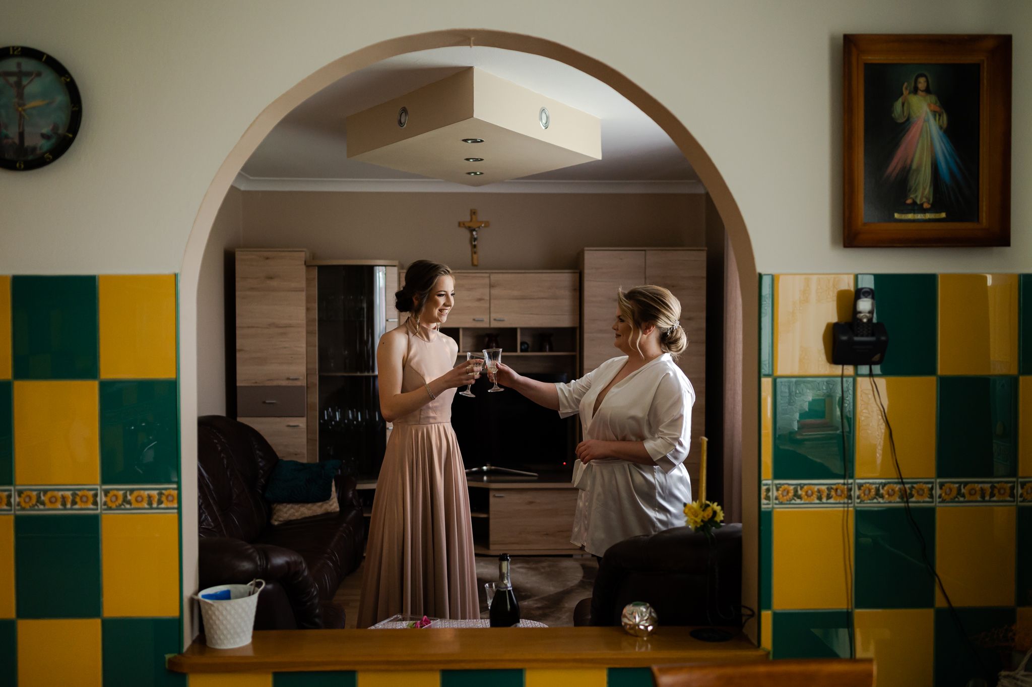 Dwie kobiety wznoszące toast w kolorowym tradycyjnym wnętrzu z żółto-zielonymi kafelkami i łukiem