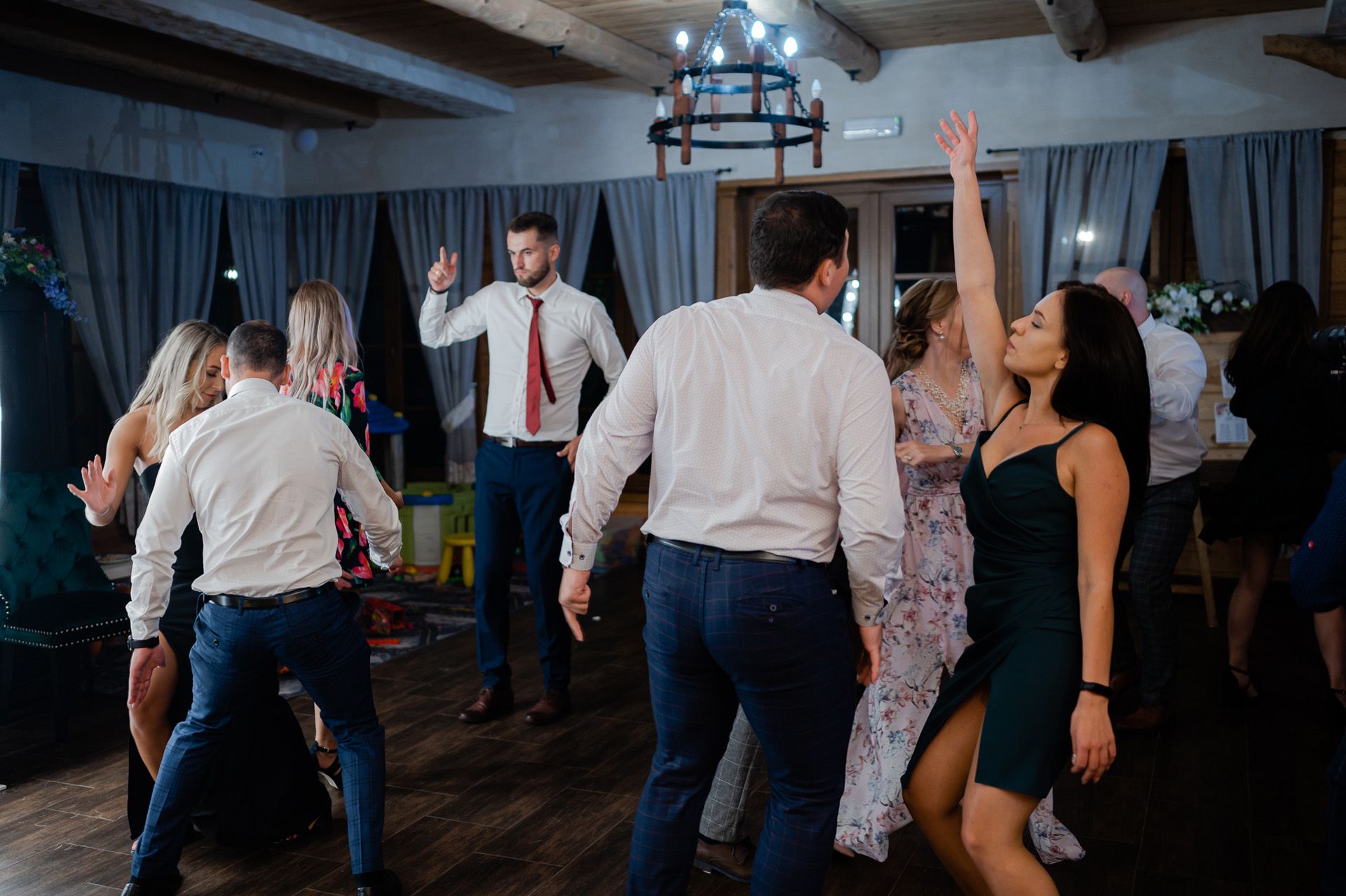 Taniec weselny w stylowej karczmie z drewnianymi belkami i żyrandolem, tradycyjna atmosfera wesela ludowego